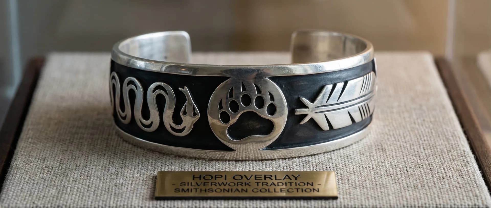 Hopi overlay silver bracelet at macro scale showing hand-cut clan symbols casting shadows on the oxidized layer