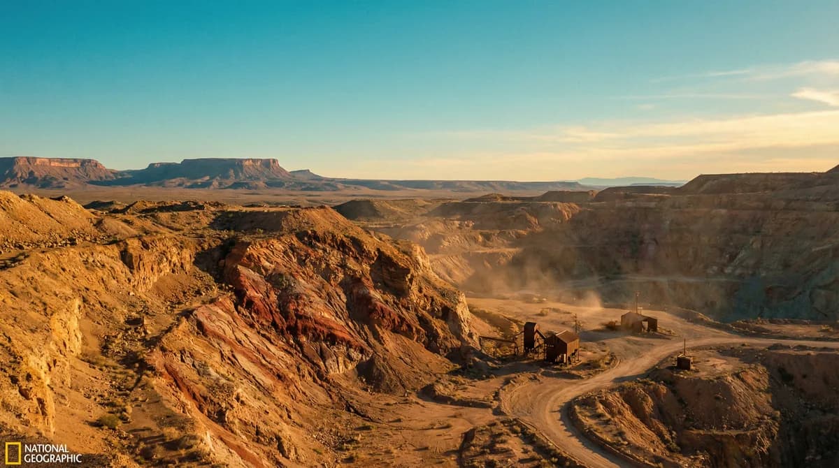 Wide landscape of the Kingman mine area with exposed mineral veins and distant mesas under golden hour light
