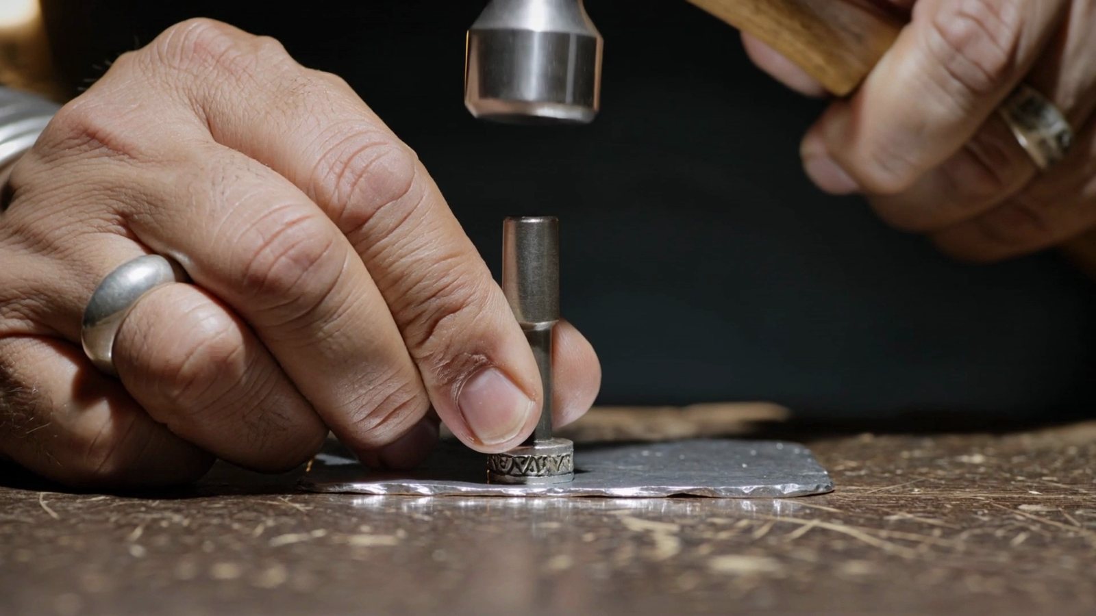 A silversmith’s hands strike a stamp into sterling; then the real JOE PAUL hallmark on the back of white buffalo pendant No. 019, and the pendant itself